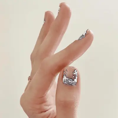 A manicure with a pale pink base and pink, white, and orange swirls