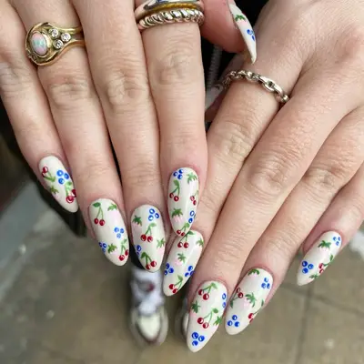 Long nails with delicate fruit and floral nail art.