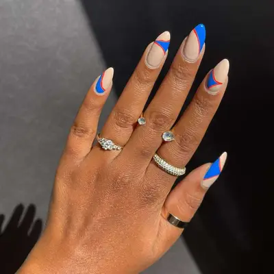 Nude nails with contrasting blue and red design.