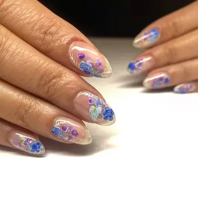 Negative-space floral nail designs in blue and purple hues