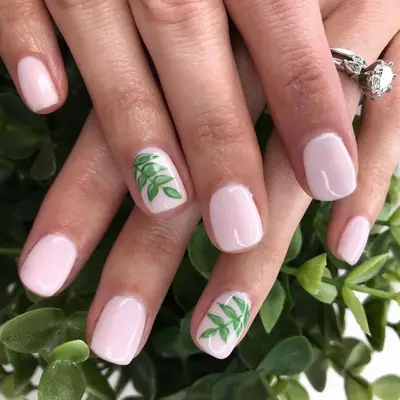 Short pink nails with a green fern on each ring finger nail