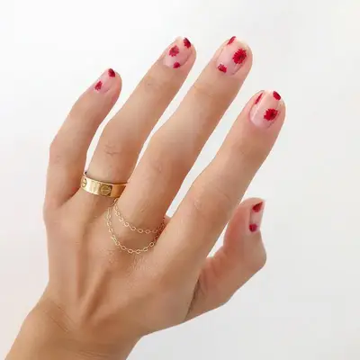Short nude nails with bright red blooms dotted all over