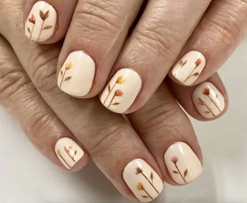 Short cream-colored nails with autumnal-hued flower buds