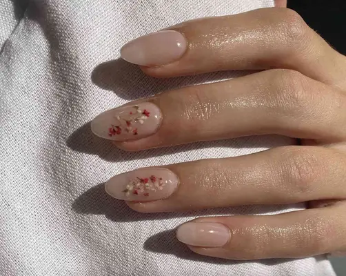 Nude manicure with dainty pressed flowers on the middle and ring finger nails