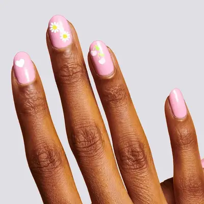 Rounded pink nails with hearts, cherries, and daisy nail art