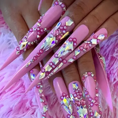 Close up of Cardi B with her hands near her face, featuring long red nails with jewels