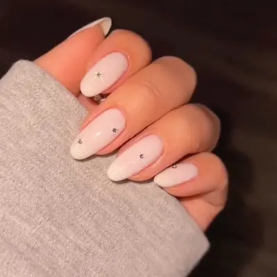 close up of milky white nails with rhinestones and stars