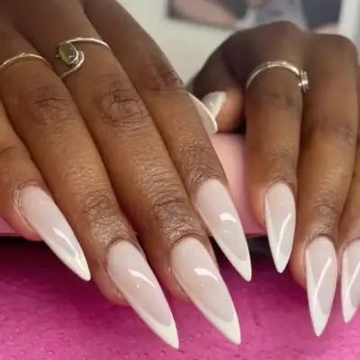 close up of long pointy nails in milky white hue with white french tips