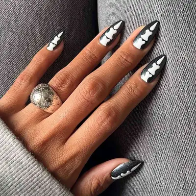 a glittery black manicure topped with bone nail art 