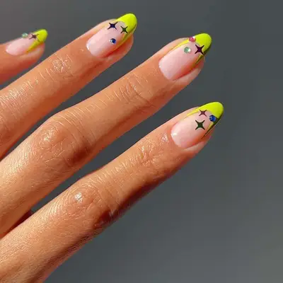 Neon yellow-green French manicure with multicolored star and gem details