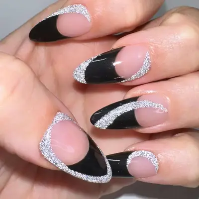 Stiletto manicure in black and neutral tones with glitter accents