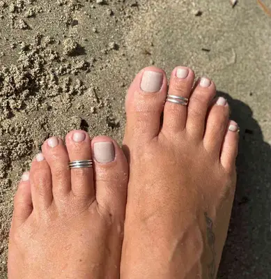 Feet in the sand with tan polish on toees