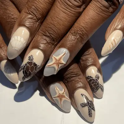 Close up of beige nails with sea turtle and starfish nail art.