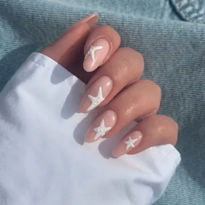 Close up of nude oval nails with white starfish nail art.