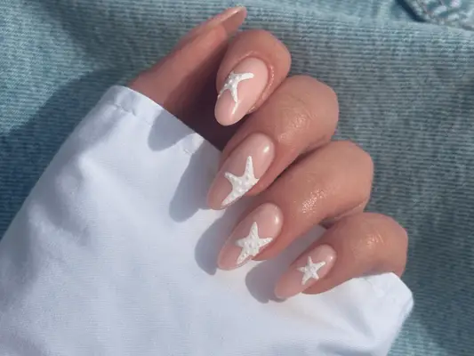 Close up of nude oval nails with white starfish nail art.