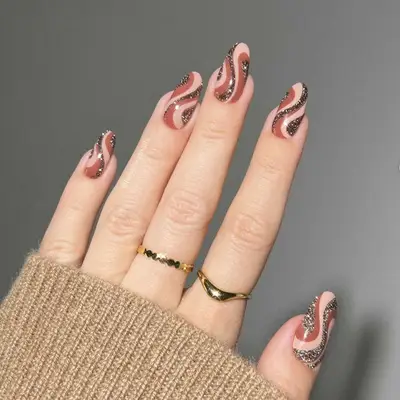 Close up of a manicure with swirls in neutral tones and glitter