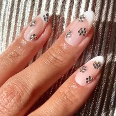 a french manicure with diamond rhinestone accents in the shape of flowers