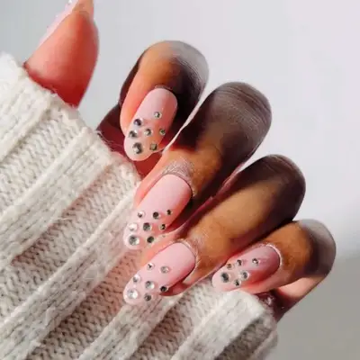 a neutral manicure topped with rhinestones toward the ends of the nails
