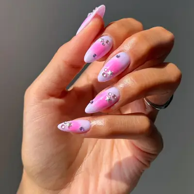a pink and lilac aura manicure topped with diamonds and charms