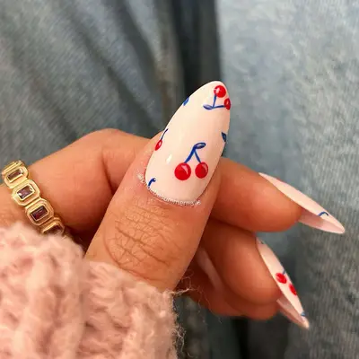 a white manicure with classic red cherries with blue stems
