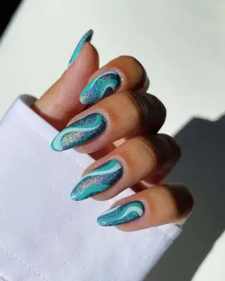 a glittery aqua manicure topped with turquoise and seafoam swirls
