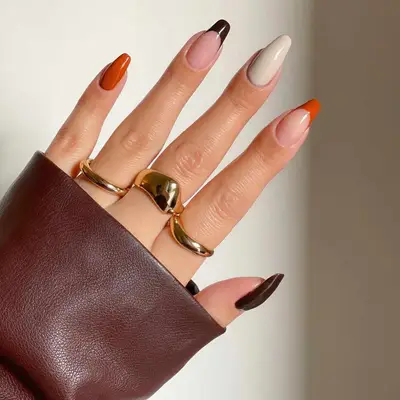 A mismatched manicure with French tips, pumpkin spice, and neutral colors