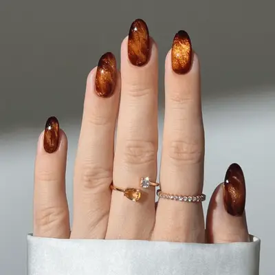 Close up of a solid pumpkin spice manicure against a white background