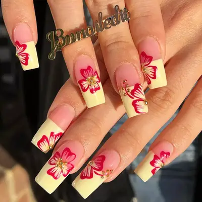 Close up of square yellow French nails with raspberry red hibiscus nail art.