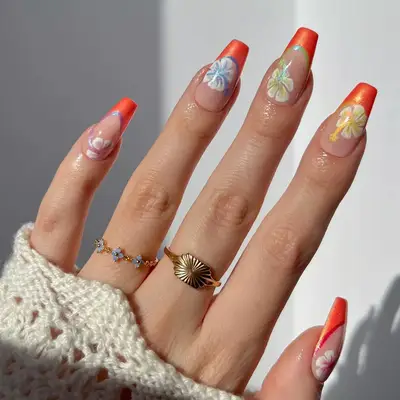 Close up of rainbow hibiscus nail art with orange French tips.
