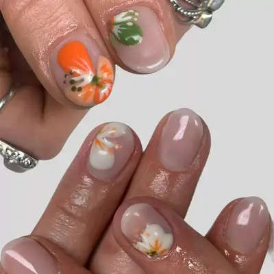 Close up of short nude nails with white and green hibiscus nail art.