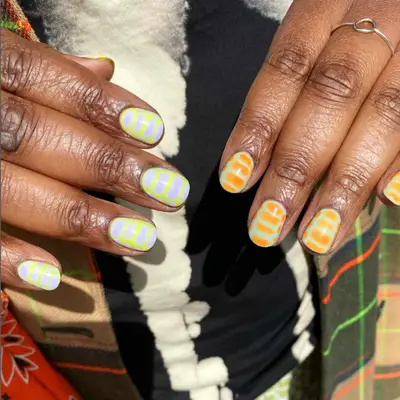 Croc print nails in purple and green on one hand and orange and green on the other.