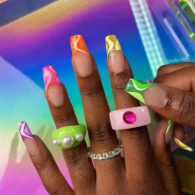 French tip nails in purple, pink, orange, yellow and green with swirls.