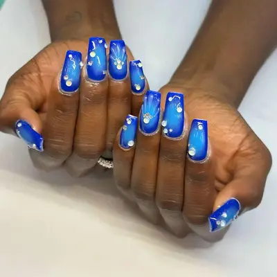 Dark and light blue nails with gemstones and seashell design.