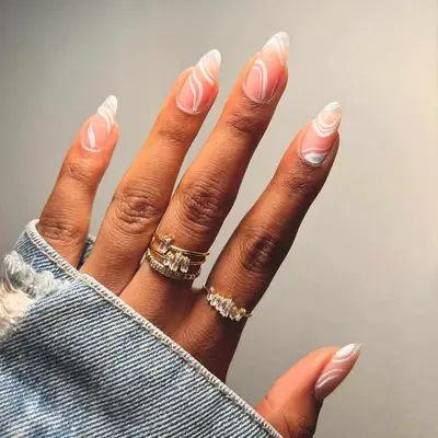 White swirl nails on a sheer milky base with four rhinestone rings