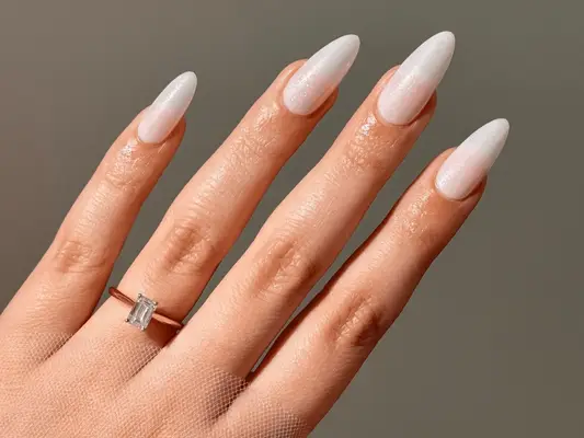 Long almond nails with a shimmering glitter white nail polish.