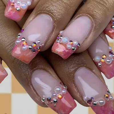Orange and pink swirled tips french mani with rhinestones