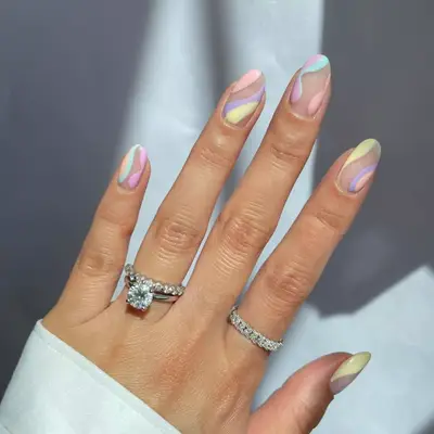 Negative space manicure with pastel swirls in yellow, purple, lavender, light blue, pink, orange.