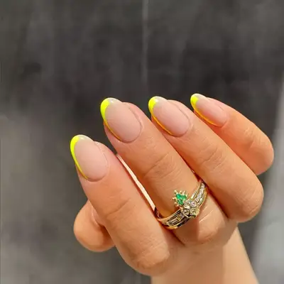 Nude manicure with half the nail outlined in yellow.