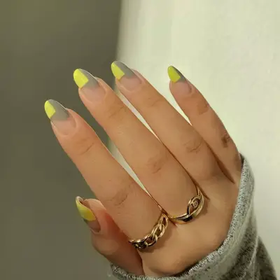 Yellow and gray geometric shapes on a manicure.