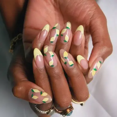 French manicure with yellow tips on two fingers and lemons on the others.