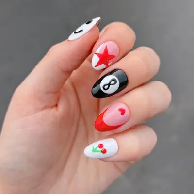 Manicure with different red designs including red star, red French, and cherries