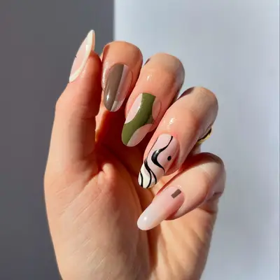 a mismatched manicure with negative space and brown, green, and black accents