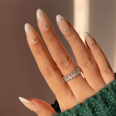 Champagne French manicure with silver outline and celestial gems.