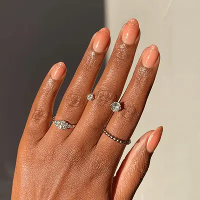 Short oval nails with a pink champagne glitter ombré fade from the tip of the nail down.