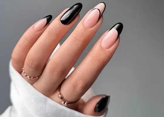 Hand with long round nails and black mismatched manicure