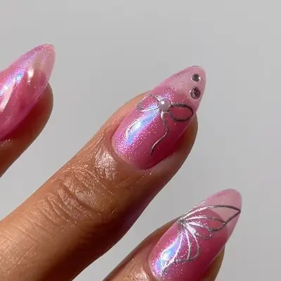 A pink jelly manicure with bow, butterfly wing, and rhinestone details