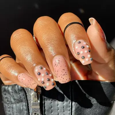 a nude manicure with pearl and gunmetal stud accents