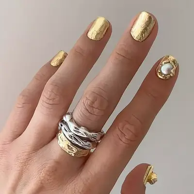 a gold foil manicure with freshwater pearl accents