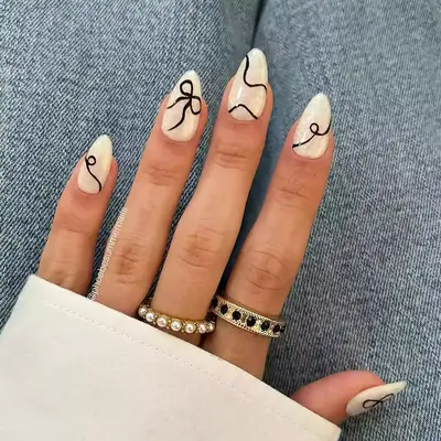 a pearly manicure with a black ribbon bow accent