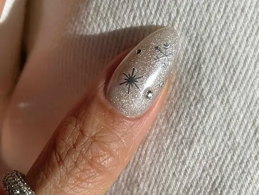 a shimmery white thumb nail with snow and rhinestone details